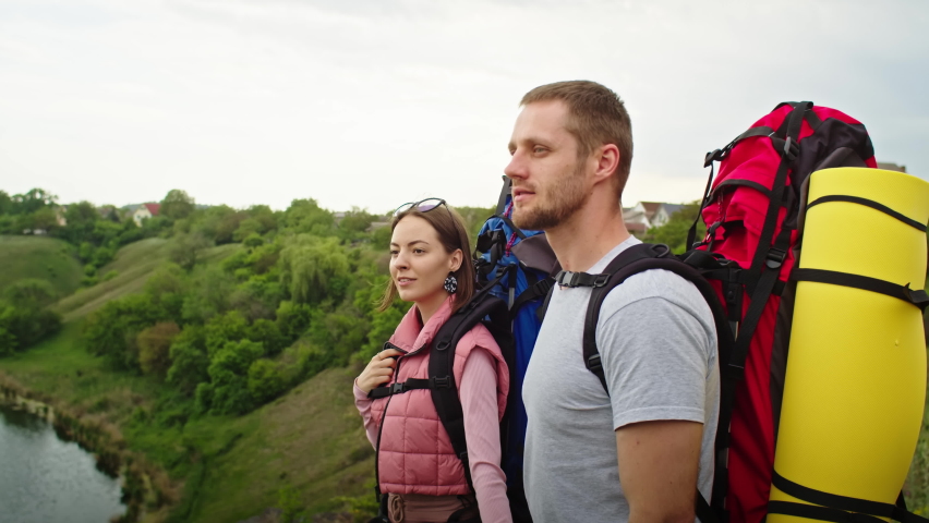 Happy couple, man and woman in the mountains, travel in search of a vacation spot. they rejoices, standing against the backdrop of a beautiful landscape. vacation in the mountains. | Shutterstock HD Video #1091616301