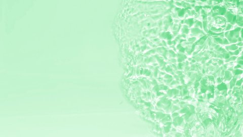 Crystal clear water background. Pure blue water with light reflections in slow motion. Natural texture top view. Slow motion full HD video banner toned in light green or mint color