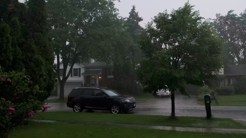 Wide shot of Heavy rain, with loud thunder and lightning, a suburban residential street. Slow motion footage
