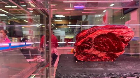 Marbella , Malaga , Spain - 06 19 2022: Big piece of red dry aged beef, rib eye at a butcher, steak in a glass store window vitrine, 4K shot