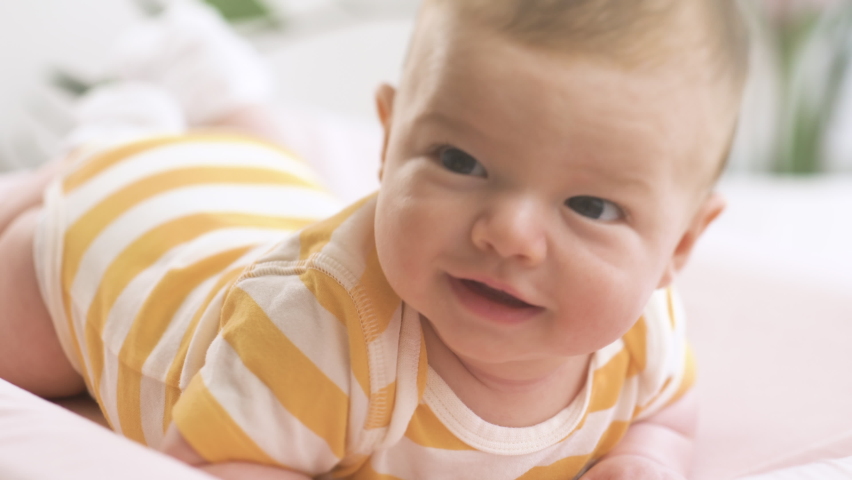Newborn little baby lying on the bed and smiling with a nice soft focus background.