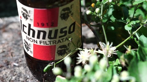 Bracciano, Italy - July 25, 2019: Empty Ichnusa beer bottle left on a wall with flowers. famous Sardinian beer, produced in Assemini. From the Latin name of Sardinia, Hyknusa