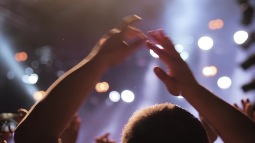 Man silhouette partying, cheering, raising hands up and clapping at rock concert in front of stage of nightclub - close up. Bright colorful stage lighting. Nightlife and entertainment concept Royalty-Free Stock Footage #1091628951