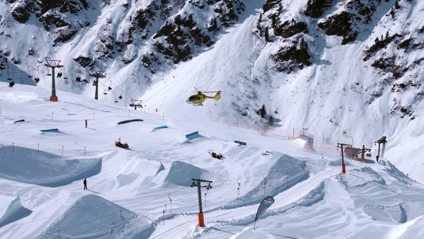 Rescue helicopter landing on the slopes helping skier in a ski park. Air ambulance in Alps. Rescue transportation.