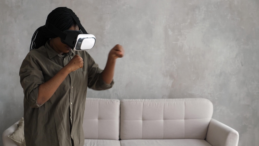 Beautiful active young woman in a virtual reality helmet. Person touches something using modern virtual reality glasses indoors. Augmented Reality | Shutterstock HD Video #1091633799