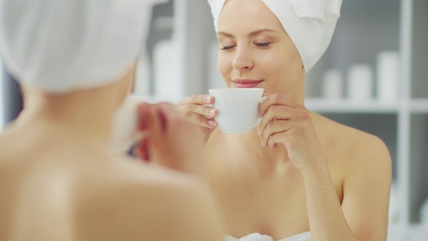 Young Girl is Sitting in front of a Make-up Mirror in the Bathroom and Applying a Skin Cream. Beautiful Woman is Making Cosmetic Rejuvenation Procedures. Health and Beauty Concept.