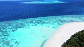Tropical atoll island in Maldives with coral reef and turquoise sea water. Touristic vacation holidays travel destination. Scenic seascape. Drone aerial video footage.