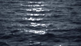 Blurry defocused 4k stock video of sunny sunset sea water waves. Natural organic textured black and white blur background