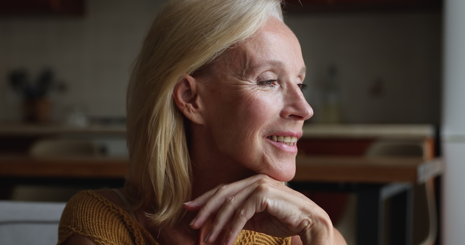 Happy thoughtful dreamy mature blonde woman looking away, touching chin, smiling at good thoughts, relaxing at home, enjoying comfort, thinking over good news. Elderly age concept Royalty-Free Stock Footage #1091639017