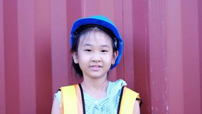 4k slow motion video of asian kid cute girls and happy, wear a helmet standing next to the container. concept of education and enhancing skills as an engineer in childhood.