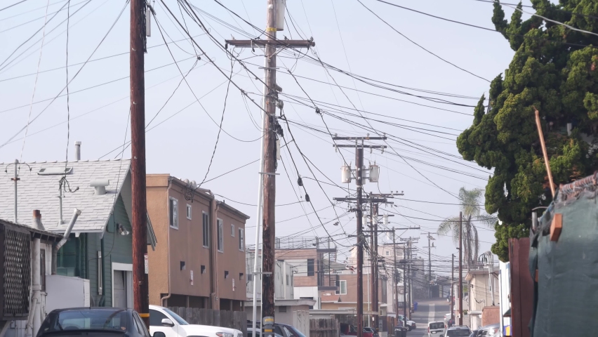 Power lines or wires on poles, foggy city street, California, USA. Cables on high voltage wooden electricity posts or pylons in misty San Diego. Power supply and houses in America. Cloudy weather. Royalty-Free Stock Footage #1091646001