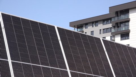 Solar panel photovoltaic cells with apartment building in background, concept of renewable and alternative energy, selective focus