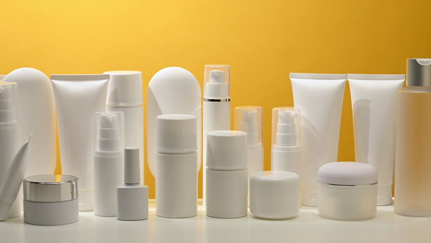 Jar, bottle and empty white plastic tubes for cosmetics on a yellow background. Packaging for cream, gel, serum, advertising and product promotion | Shutterstock HD Video #1091651921