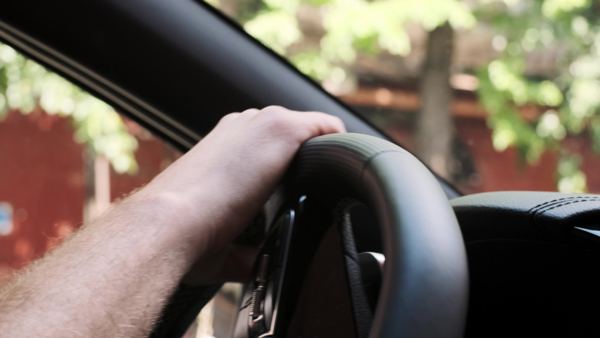 Handheld close up view of man hand turning steering wheel in car driving through city. unrecognizable man turns steering wheel in car and drives around town. | Shutterstock HD Video #1091654631