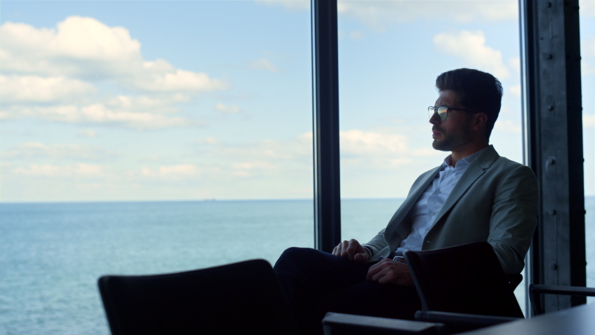 Young businessman looking panorama window. Pensive man considering problems resting at sea view. Stressed guy ceo thinking making future decisions. Concerned client waiting manager lawyer alone. | Shutterstock HD Video #1091654697