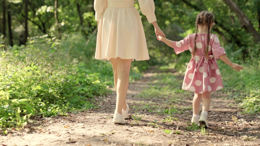 Happy family walk in forest, kid, girl, mom outdoors. Mom, are walking together holding hands in park.  | Shutterstock HD Video #1091655621