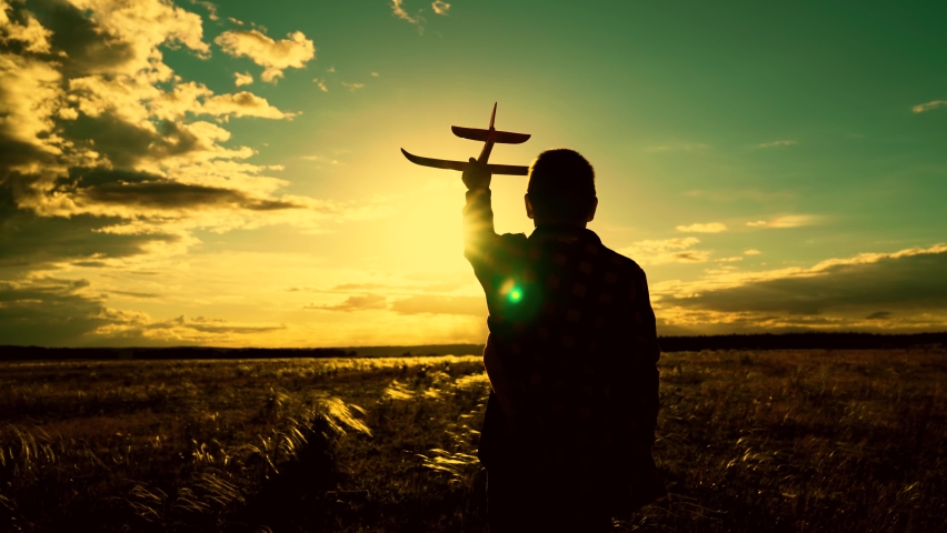 Child dreams of flying and becoming pilot. Boy wants to become pilot and astronaut. Slow motion. Happy boy runs with toy plane across field in rays of sunset. Children play with toy airplane. Kid run | Shutterstock HD Video #1091655705