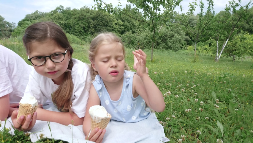 Children eat ice cream in the park and spend time together, summer holidays