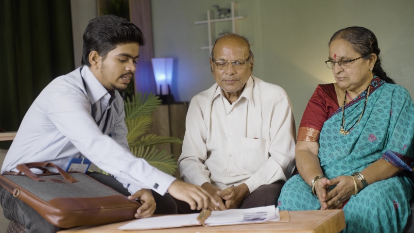 Banker advising about insurance to elderly couple while sitting on sofa at home - concept of banking, financial and communication. Royalty-Free Stock Footage #1091661443