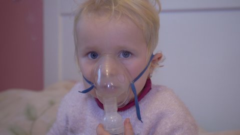 child wearing a nebulizer mask,little girl treats cough at home