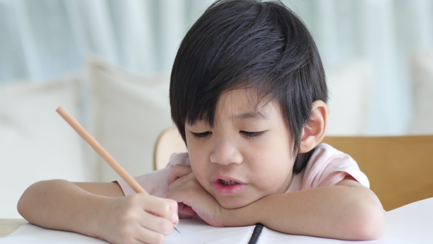 Unhappy Asian child working on hard homework at home alone - Powered by Shutterstock - Get 15% off with code: PIKWIZARD15