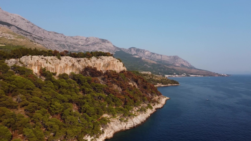 Rocky coastline of Croatia with turquoise water at sunset, near the city of Makarska. Aerial view of city Makarska and epic mountain. Adriatic coast aerial view in high quality 4k. Royalty-Free Stock Footage #1091678375