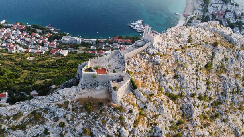 Omis, Croatia. Aerial view on old fort at mountain near old pirate city Omis. Castle on mountains over Adriatic coast at sunset. Top panoramic view high quality 4k. Royalty-Free Stock Footage #1091679175