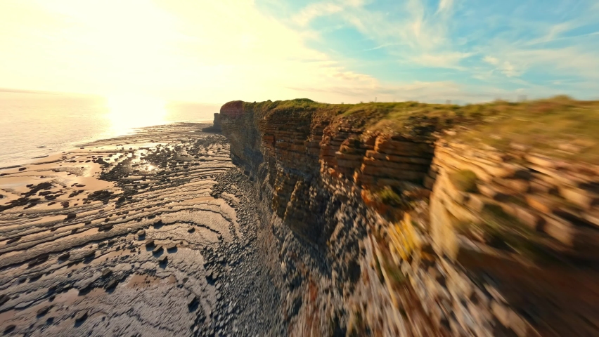4K FPV Aerial view of monk nash beach known as the jurassic coast, stunning fast flying low across golden sandy beach with cliff side on the right. Royalty-Free Stock Footage #1091684095