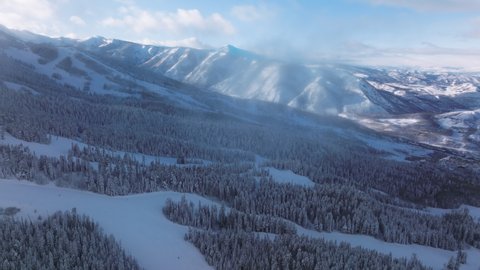 Drone footage of the vivid blue skyline above mountain peaks covered in snow. Panoramic view of a popular winter resort location for skiing and snowboarding. High quality 4k footage