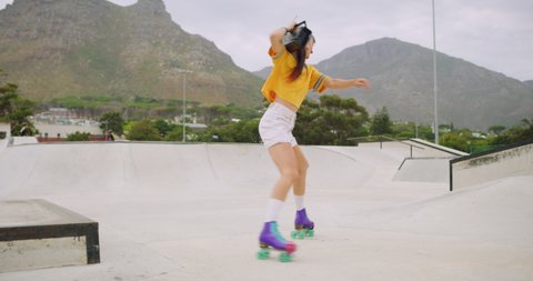 Female roller skater with a boombox dancing in a skate park outside, spinning and moonwalking backwards having fun. A cool urban skater full of energy listening to music on a radio on her shoulder