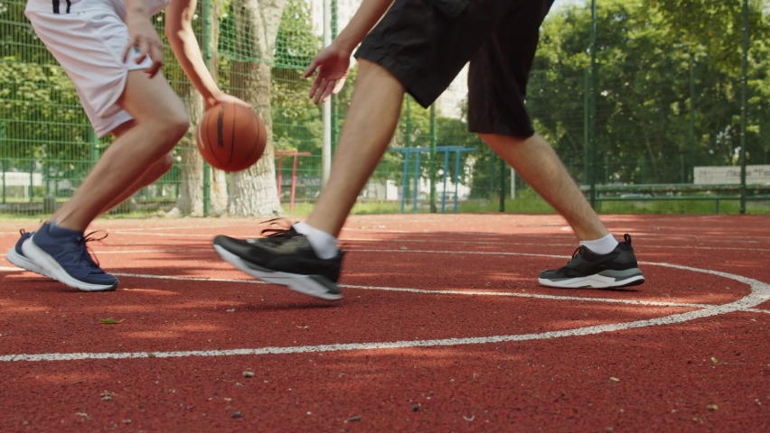 People playing street basketball during a warm summer day. Two teens playing a basketball match on an outdoors court during a sunny summer day.  Attack and defence, no shot. Royalty-Free Stock Footage #1091691325
