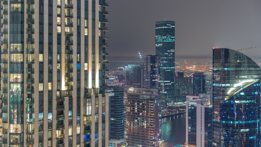 Aerial panoramic view of a big futuristic city night timelapse. Business bay and Downtown district with many skyscrapers near canal, Dubai, United Arab Emirates skyline.