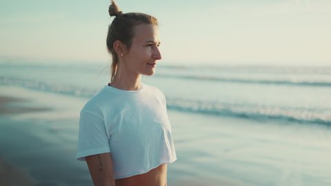 Beautiful blond woman walking along the sea after yoga practice. Sporty girl looking good enjoying morning on the beach