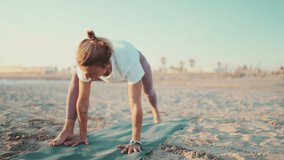 Beautiful healthy woman on mat doing warmup exercise. Young yoga teacher stretching during yoga practice on the beach
