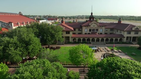 Fort Worth , TX , United States - 06 17 2022: Fort Worth Live Stock Exchange Building and American flag in Ft Worth. Aerial of grounds in golden hour light.