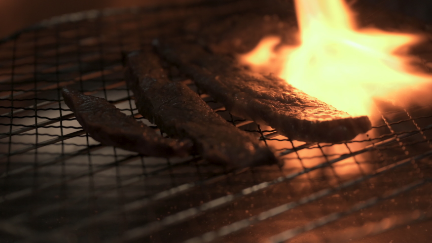 Chef Grilled Wagyu beef.,Juicy beef steak is fried on fire coals on iron grill on dark background in flame of smoke. Royalty-Free Stock Footage #1091702255