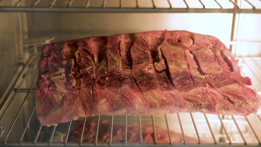 Big piece of red dry aged beef, rib eye at a butcher, steak in a glass store window vitrine, 4K Royalty-Free Stock Footage #1091702257