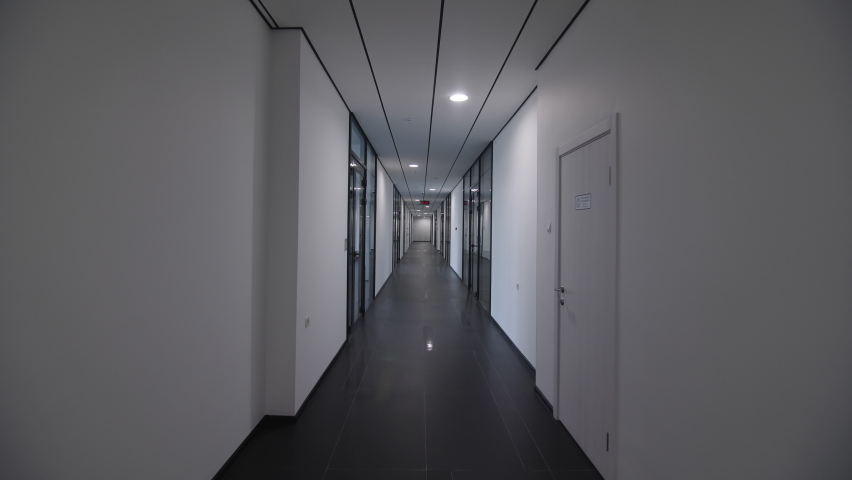 Motion along empty brightly illuminated corridor between spacious offices and classes in contemporary business center
