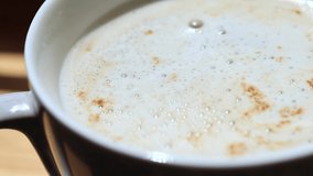 Morning cup of coffee. Latte in a white cup, zoom video. Invigorating drink with foam
