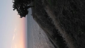 Sunset over the sea, view from cliff, vertical footage, sea surface ripples