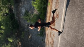 Triathlete running outdoors. Vertical video. Male athlete jogging on road in sunny morning. Young muscular active man doing intense run workout training, running fat. Endurance running. Sport concept