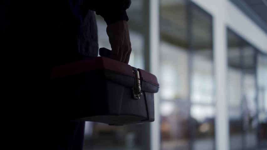 Man carries toolbox and multimeter tester. Electrician goes to repair light in office. Master finishes work on electricity. Male mechanic in uniform. Royalty-Free Stock Footage #1091719675