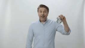 Character portrait of young man holding a small desk clock. The man shows that time has passed and it is necessary to use time well. Young man draws attention to aging. - Powered by Shutterstock - Get 15% off with code: PIKWIZARD15