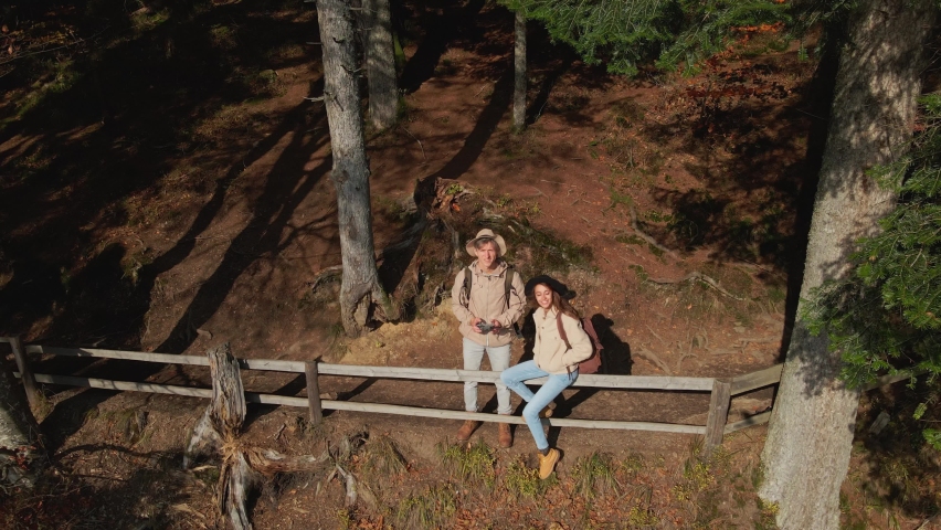 aerial drone footage of man and woman hikers sdanding on shore of famous mountain lake Synevir in Carpathian mountains, Ukraine. happy girl and man enjoys scenery landscape together.