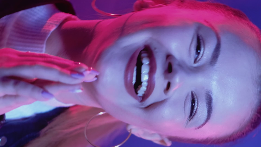 Nightclub party. Happy woman. Neon light portrait. Amused pretty female enjoying dancing in purple lights. Vertical video. Royalty-Free Stock Footage #1091723337