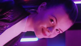 Female portrait. Disco lights. Stylish look. Peaceful beautiful woman enjoying nightclub in purple neon light glow. Vertical video.