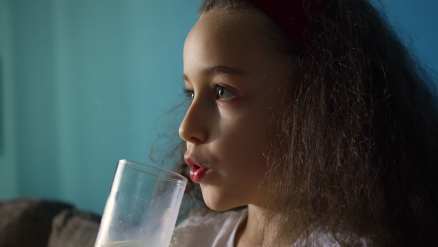 little girl child drinking milk. healthy eating a child eating breakfast kid dream concept. Daughter girl in living room on sofa drinks yogurt milk and kefir licks her lips. positive kid smiling  Royalty-Free Stock Footage #1091726843