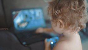 Happy pretty toddler boy playing video game home. Sweet Child control game controller. Small baby gamer kid with help joystick control panel play computer game. Video game console playing home