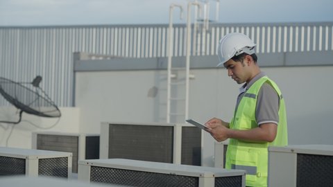 Utility Engineers are inspecting the air conditioning system on the roof deck of the factory. The designer of the refrigeration system of the factory walked to check the system operation