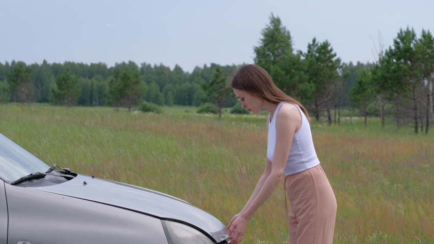 Confused young woman checking her broken car in nature.  | Shutterstock HD Video #1091733583
